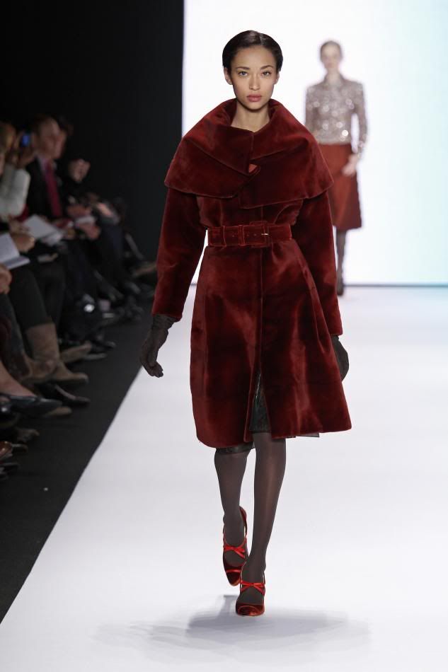 24. Anais: Rust sheared mink coat with caplet collar and rust velvet belt and black suede gloves.